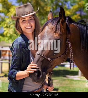 Il migliore rubato una donna potrebbe desiderare. Ritratto di una giovane cowgirl in piedi con il suo cavallo. Foto Stock