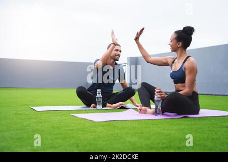 Adattabilità e sensazione totale. Scatto di un giovane sportivo uomo e donna che si danno un alto cinque mentre si esercita all'aperto. Foto Stock