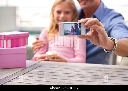 Lei non sarà una bambina per sempre. Un taglio corto di un uomo che scatta una foto di se stesso e di sua figlia giovane al suo compleanno. Foto Stock