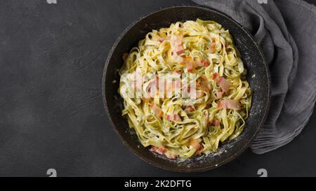 Carbonara all'uovo italiana in padella nera con pancetta, parmigiano, spezie ed erbe aromatiche Foto Stock