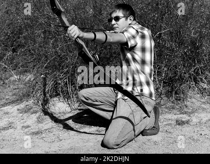 Giovane ragazzo che spara un arco e una freccia Foto Stock