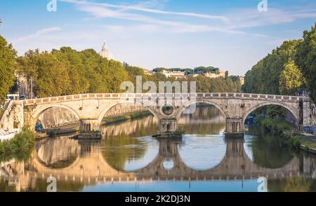 Ponte sul fiume Tevere a Roma, Italia. Cupola della Basilica Vaticana sullo sfondo con luce dell'alba. Foto Stock