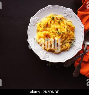 Tagliatelle con crema di zucca salsa sopra lo sfondo nero.vista superiore Foto Stock