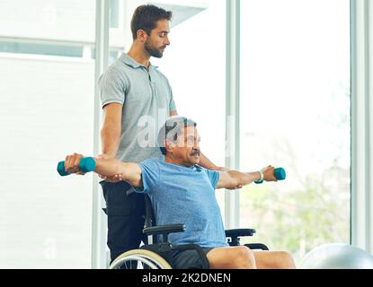 Basta tenerlo lì. Scatto corto di un giovane fisioterapista maschile che assiste un paziente anziano in guarigione. Foto Stock