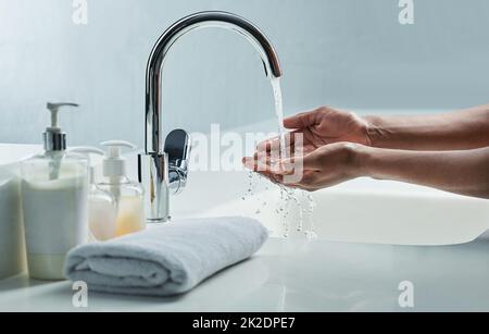 Germi e batteri giù lo scarico. Scatto corto di un uomo che lava le mani in un lavandino del bagno. Foto Stock