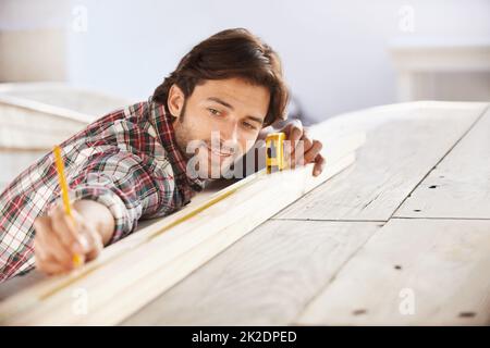 Perfetto. Un bel carpentiere giovane che misura e segna il legno. Foto Stock