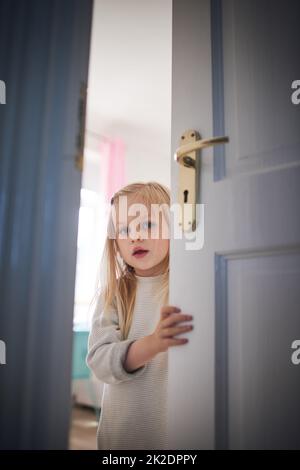 Bussare, dove c'è. Scatto di una bambina adorabile che apre una porta a casa. Foto Stock