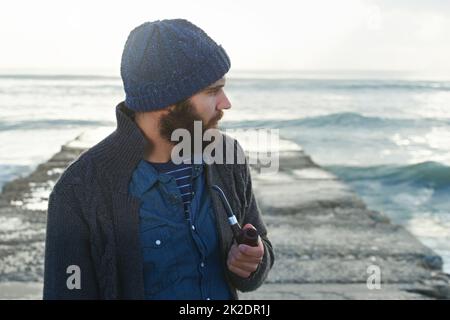 Fumare un tubo. Scatto corto di un uomo bearded che fuma un tubo fuori. Foto Stock