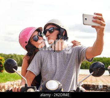 Ricordi sempre in viaggio. Scatto di una giovane coppia che prende un selfie insieme mentre fuori per un giro su uno scooter. Foto Stock