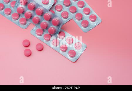 Vista dall'alto compresse rosa e blister di pillole su sfondo rosa. Farmaco da prescrizione. Vitamine, minerali, ed integratori. Industria farmaceutica. Sanità e medicina. Prodotto farmaceutico. Foto Stock