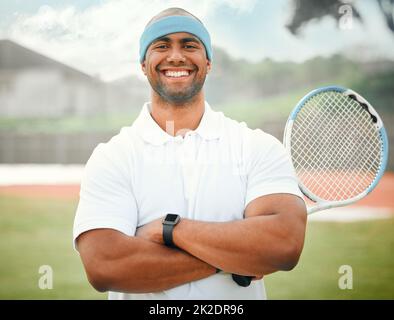 Pronto a servire una certa concorrenza. Ritratto corto di un bel giovane tennista maschio in piedi fuori con le braccia ripiegate. Foto Stock