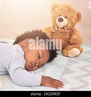 Sognate il piccolo grande. Colpo di un bambino piccolo che dorme su un letto con un orsacchiotto. Foto Stock
