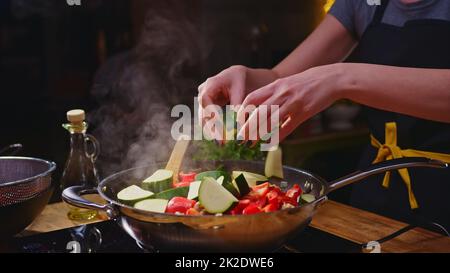 Donna che cucina friggere in cucina in una padella wok Foto Stock