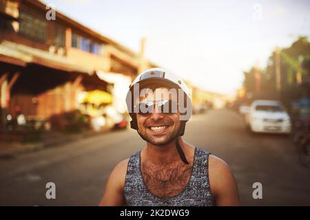 Non c'è niente di più divertente di un giro in bicicletta. Scatto di un giovane uomo che viaggia attraverso la città sul suo scooter. Foto Stock