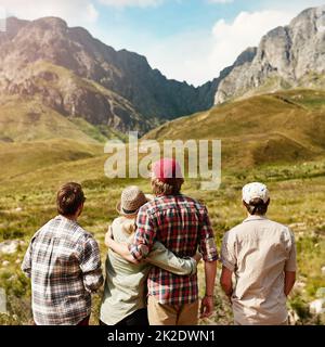 Chi meglio per apprezzare la natura che con i tuoi migliori compagni. Foto retrostenibile di una giovane coppia ammirando una vista montagnosa nella natura. Foto Stock