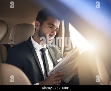 Recuperare le ultime notizie. Scatto corto di un bel giovane uomo d'affari che legge la carta mentre la mattina si reca al lavoro. Foto Stock