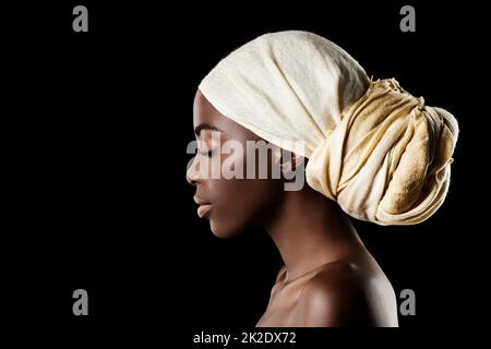 Il profilo della bellezza. Studio girato di una bella donna che indossa un foulard su sfondo nero. Foto Stock