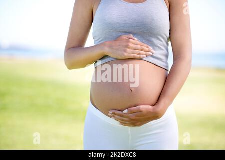 Stare in forma come un fiddle durante la sua gravidanza. Scatto corto di una donna incinta vestita con abbigliamento da allenamento all'aperto. Foto Stock