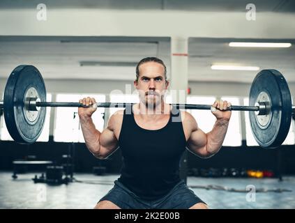 Non guardare in qualsiasi direzione, ma i vostri obiettivi avanti. Shot di un uomo che solleva pesi in palestra. Foto Stock