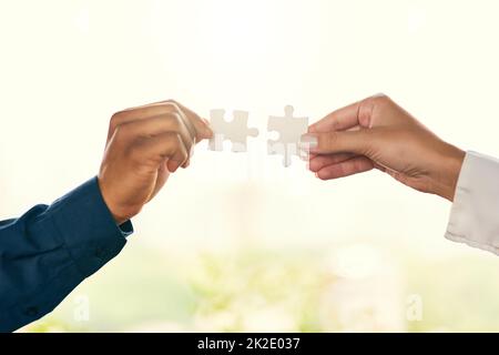 Tirare insieme per risolvere un problema. Primo piano di due persone irriconoscibili uomini d'affari che uniscono pezzi puzzle insieme. Foto Stock
