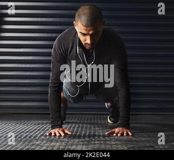 Non è più facile, si ottiene solo più forte. Scatto di un giovane atletico che fa i pushup in palestra. Foto Stock