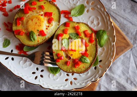 Dieta del keto. Sana prima colazione di avocado al forno e uova barche con erbe Foto Stock