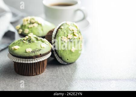 Muffin dolci con glassa al pistacchio. Dessert dolce sul tavolo da cucina. Foto Stock