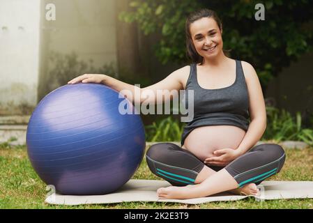 Il fitness è un migliore amico delle madri. Ritratto a tutta lunghezza di una giovane donna incinta attraente che si esercita all'esterno. Foto Stock