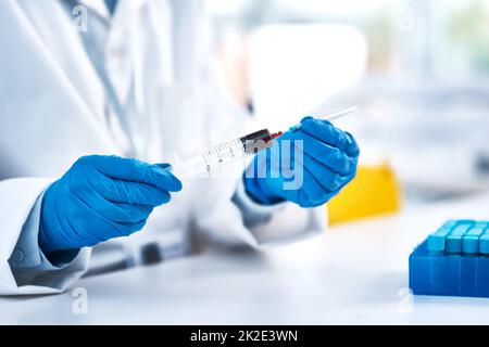 È necessario lavorare con estrema cautela in laboratorio. Primo piano di uno scienziato irriconoscibile che usa una siringa mentre lavora in laboratorio. Foto Stock