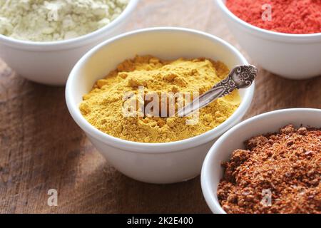 Curcuma Powder.varie spezie colorate su tavola di legno in ciotole . Cibo e ingredienti della cucina. Foto Stock