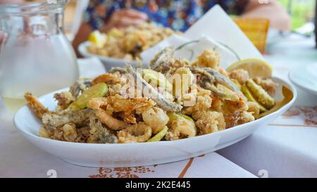 Gustoso piatto italiano fritto di pesce: Gamberi, calamari, polpi e fettine di zucchine. Foto Stock