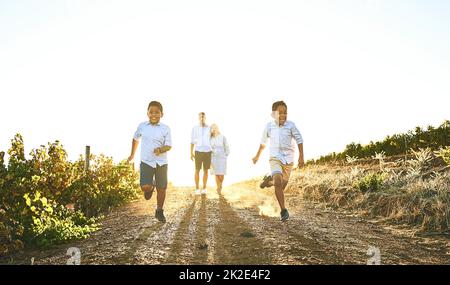 Correre per una giornata di divertimento. Scatto di una famiglia felice che si lega insieme all'esterno. Foto Stock