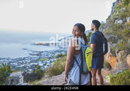 La mia vista preferita. Scatto di una giovane coppia godendo la vista del tramonto mentre fuori in un'escursione su una catena montuosa. Foto Stock