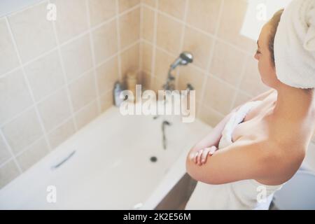 Il mio obiettivo è essere acqua saggia. Scatto corto di una bella giovane donna che si prepara a prendere un bagno a casa con le parole essere acqua saggio illustrato sopra. Foto Stock