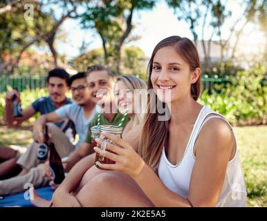 Avere il miglior tempo di sempre. Ritratto corto di una giovane donna attraente godendo un po' di bevande con gli amici all'aperto nel sole estivo. Foto Stock