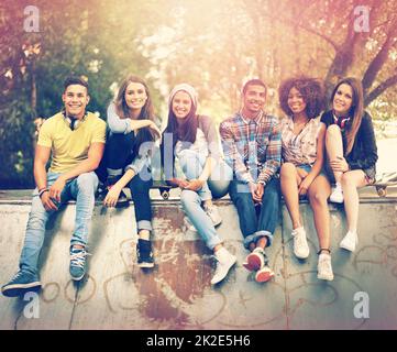 Avere un tempo freddo al loro hangout favorito. Ritratto di un gruppo di amici che si aggrappano insieme in un ambiente urbano. Foto Stock