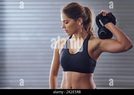 Ogni corpo merita di avere un aspetto migliore. Shot di una giovane donna che si sta allenando con i kettlebells. Foto Stock