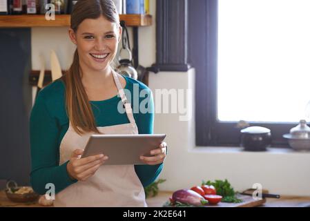 Ci sono tante ricette tra cui scegliere. Ritratto di una giovane donna alla ricerca di ricette online sul suo tablet digitale. Foto Stock