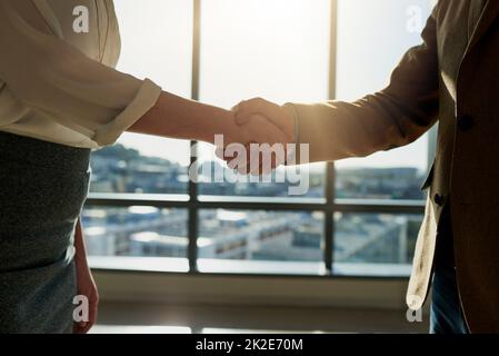 Continuate a lavorare bene. Scatto corto di due uomini d'affari irriconoscibili che scuotono le mani in ufficio. Foto Stock