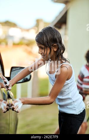 Ho fatto in modo di non perdere un posto. Scatto di una ragazza piccola allegra lavando i suoi genitori auto fuori durante il giorno. Foto Stock