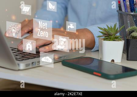 Man mano che usa il laptop per lavorare con la tecnologia e il business concept.NET ZERO icone e simboli salvare il mondo ecologico e ridurre l'inquinamento schermo virtuale. Foto Stock