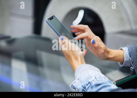 La ragazza si siede in un bar e tiene un telefono touch, un robot e la comunicazione via Internet. Vista su Serhu. Foto Stock