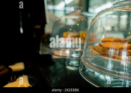 Esposizione di pasticceria in vetro con cupola di copertura nella caffetteria o nella panetteria. Pasticceria in torta al banco per il servizio a buffet nel ristorante. Pasticceria e caffè per i clienti del servizio. Foto Stock