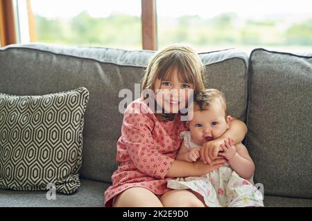 Così felice di essere una sorella grande. Ritratto di una bambina che si lega con la sorella del bambino a casa. Foto Stock