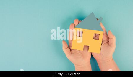 Tenendo una piccola casa di carta nelle mani, progettando di comprare una nuova casa, bene immobile, proprietà Foto Stock