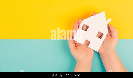 Tenendo una piccola casa di carta nelle mani, progettando di comprare una nuova casa, bene immobile, proprietà Foto Stock