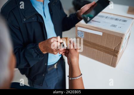 Il modo migliore e più sicuro di pagare in questi giorni. Scatto ritagliato di un uomo irriconoscibile che consegna un pacchetto a un cliente e che riceve il pagamento con una carta. Foto Stock