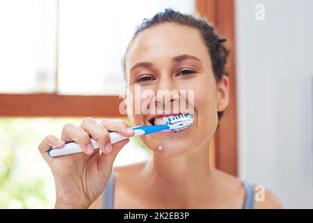 L'igiene dentale è estremamente importante. Ritratto di una giovane donna attraente spazzolando i denti a casa. Foto Stock