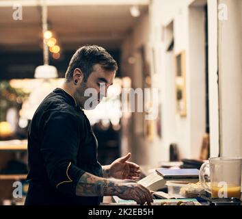 Il padrone è al lavoro. Shot di uno chef concentrato che prepara un piatto nella cucina di un ristorante. Foto Stock