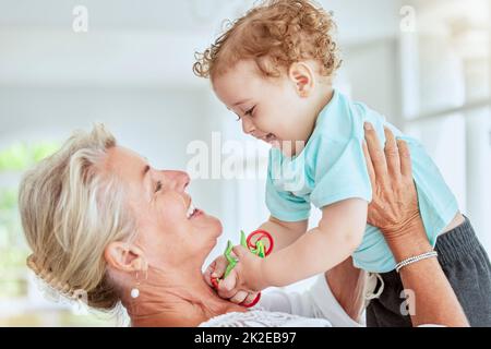 Famiglia, amore e nonna giocare con il bambino a casa legame, divertirsi e godersi il tempo di qualità insieme. Nonna alzandosi felice, sorridere e ridere Foto Stock